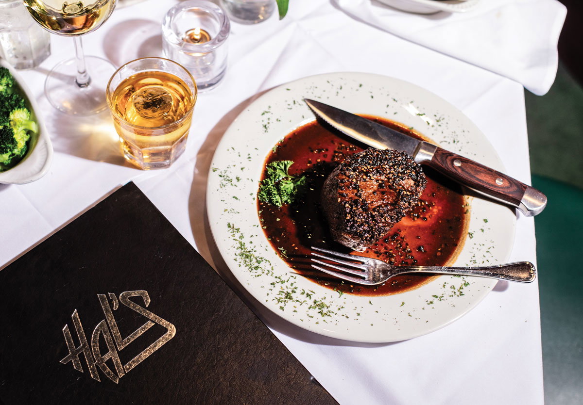 A steak sits in juice next to a Hal's menu