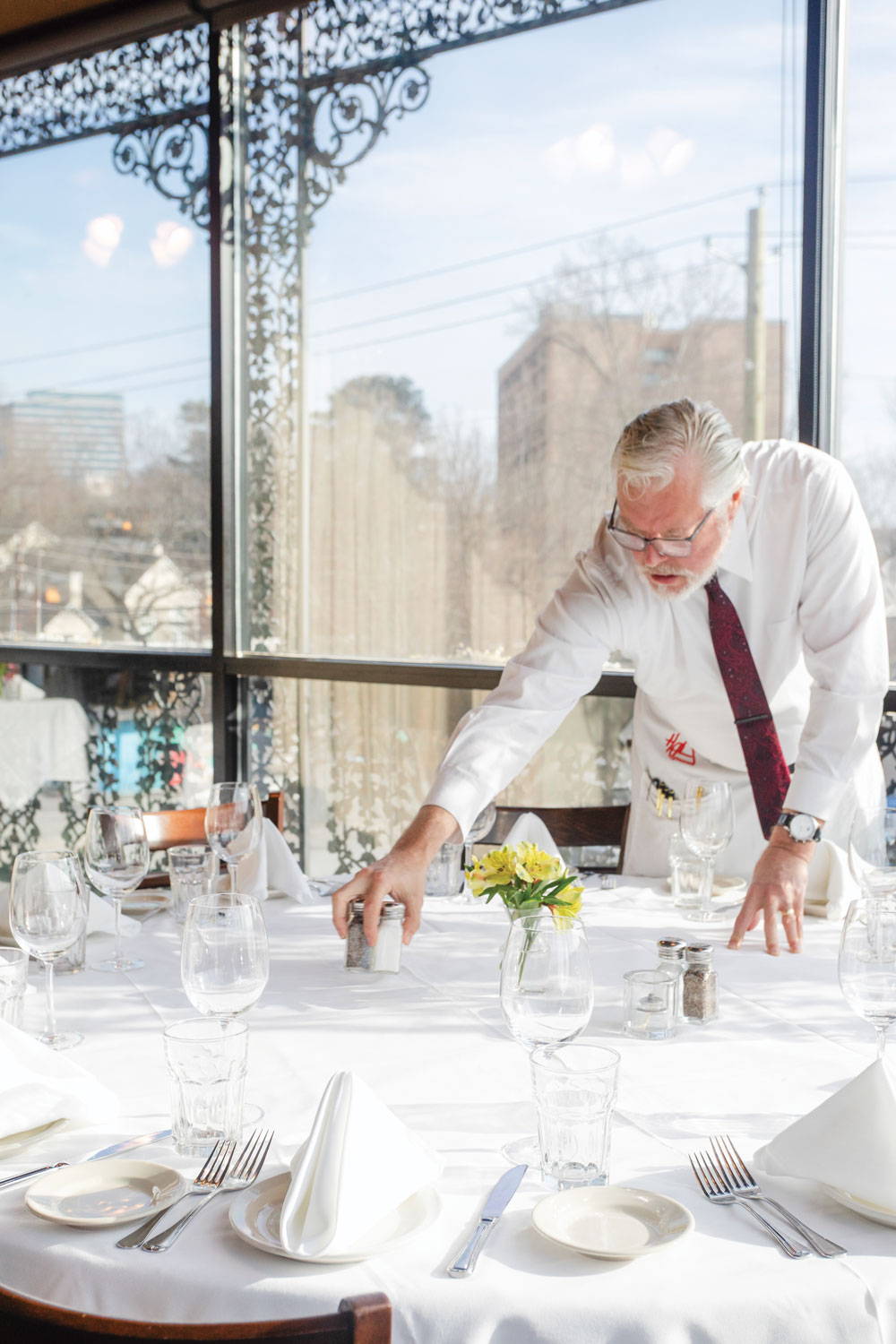 A waiter organizes a table with white tablecloth