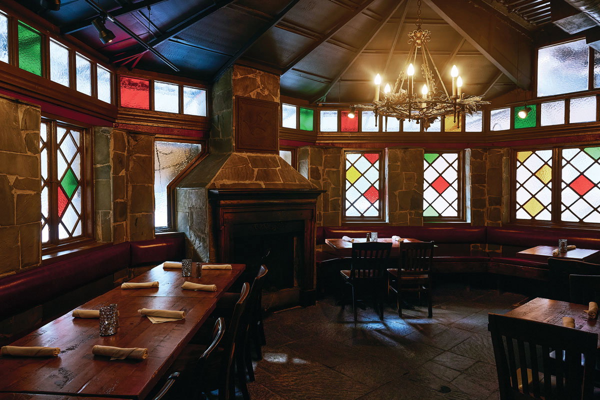 The warmly-lit interior of Highland Tap Virginia-Highland with wooden tables with stained glass windows