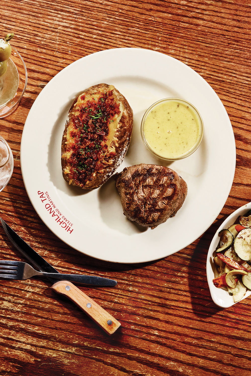 A steam and baked potato with a side of vegetables on a plate