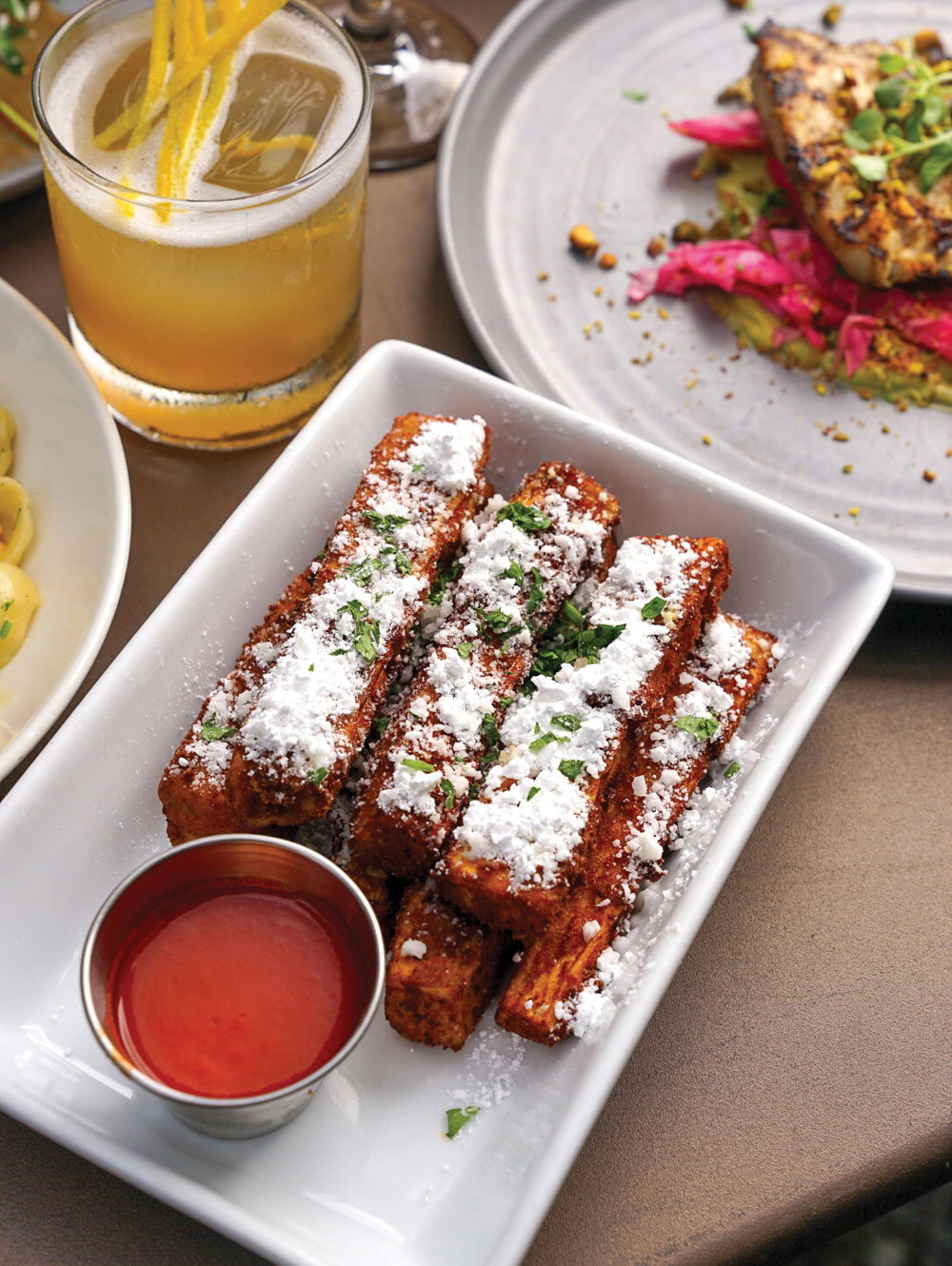 Eggplant fries covered in powdered sugar with a side of hot sauce