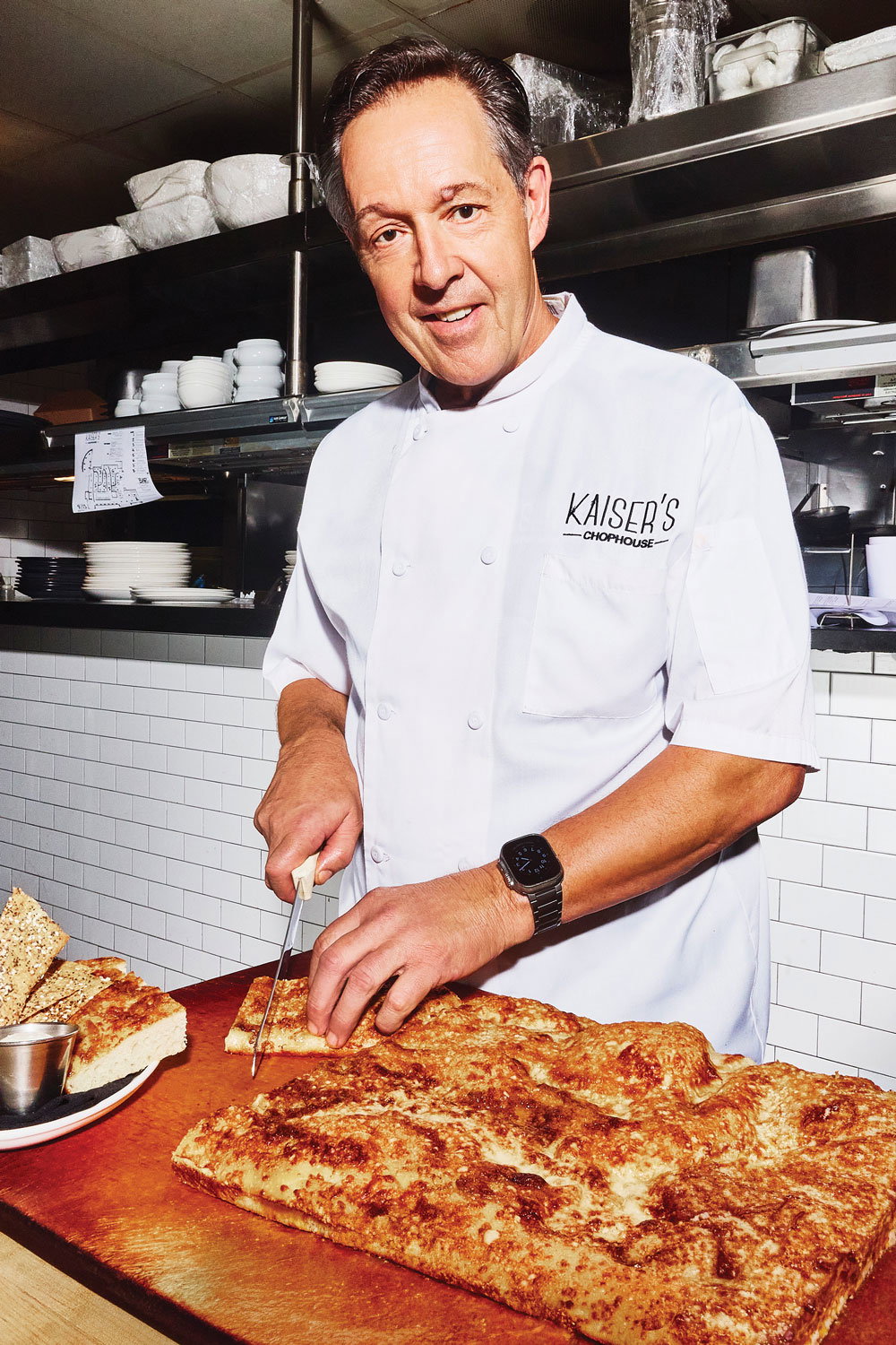 Peter Kaiser smiles at the camera while cutting bread