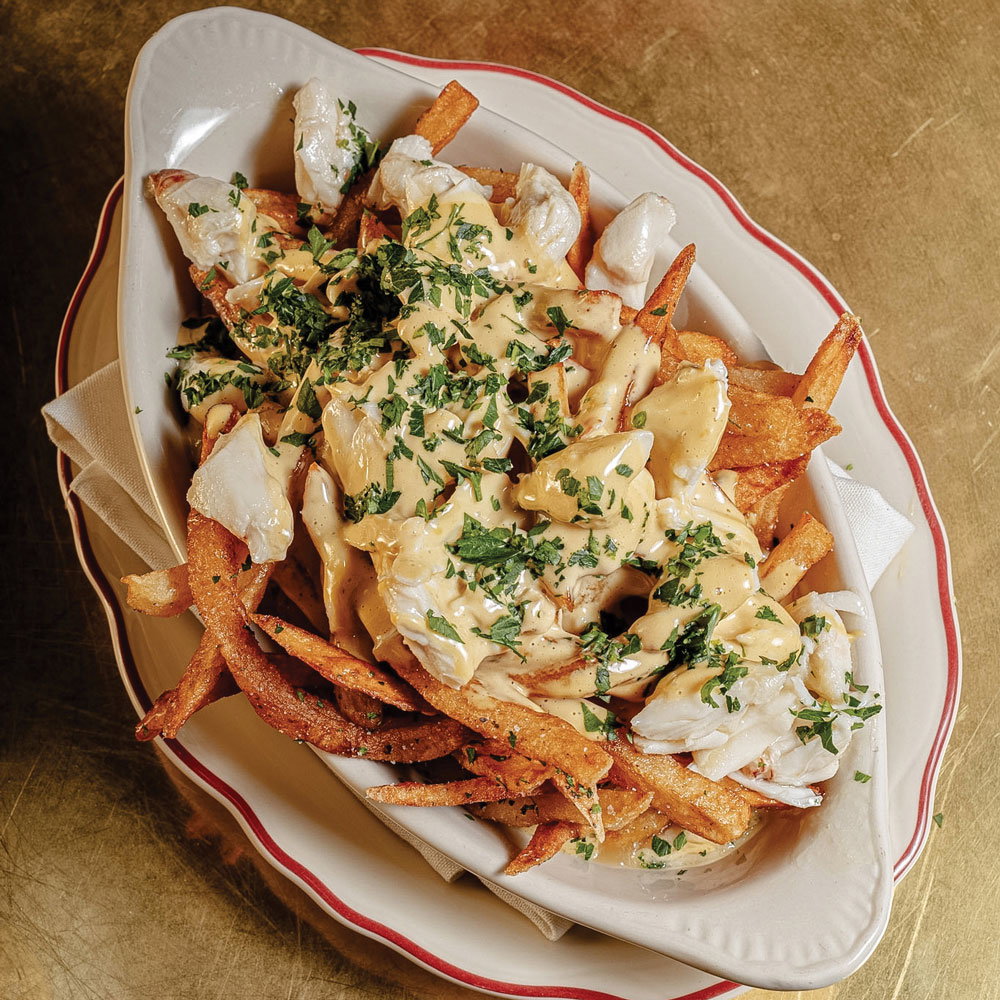 A bowl of fries topped with pasta shells and sauce