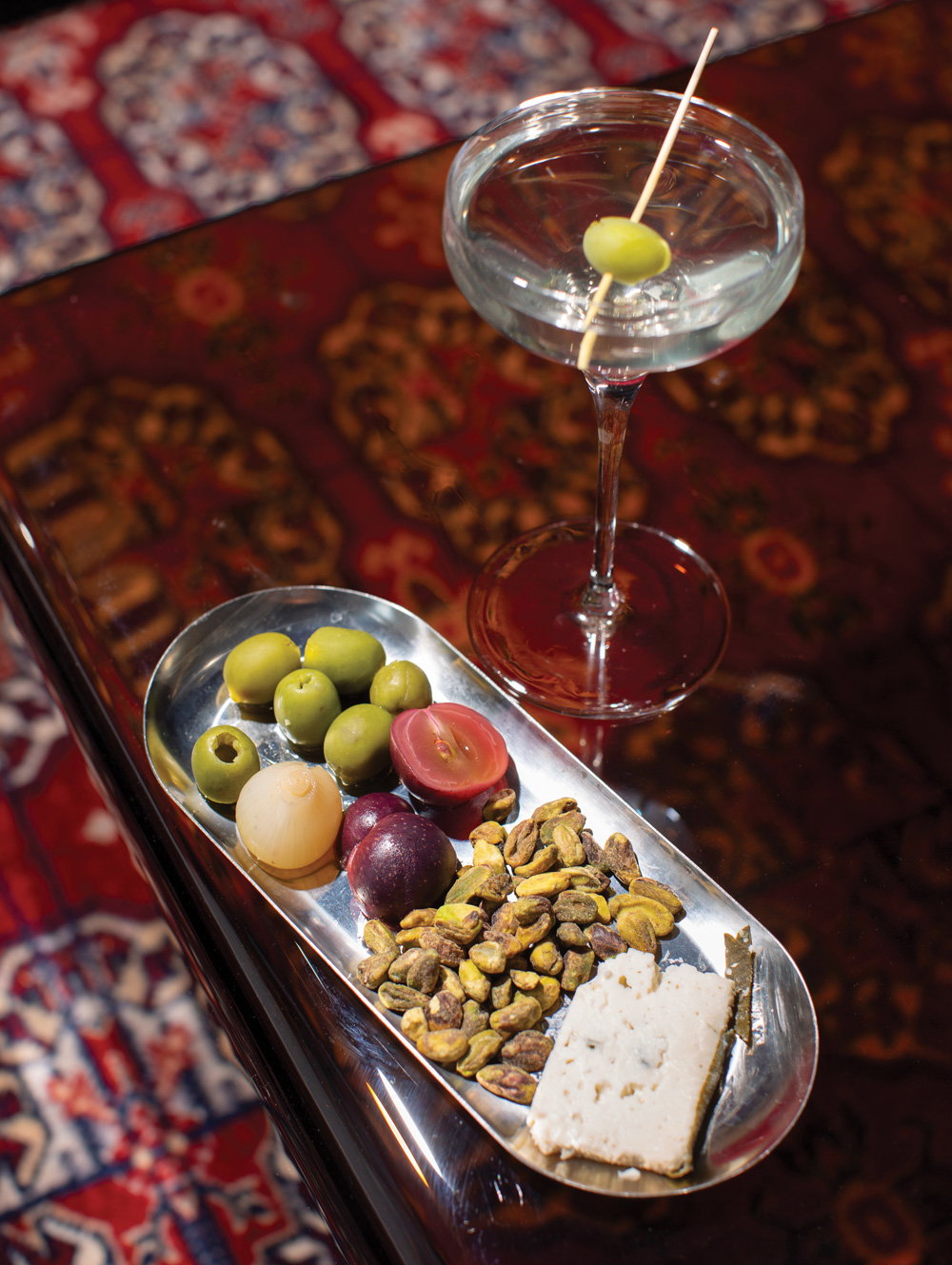 a tray with an array of snacks next to a martini glass