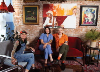 three people sit in mismatch couches against a brick wall with an array of paintings inside Last Dance