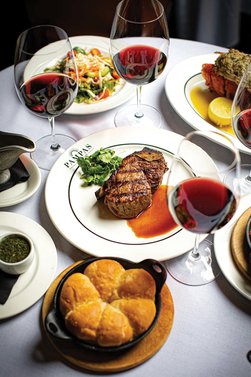 A table of dishes and glasses of red wine