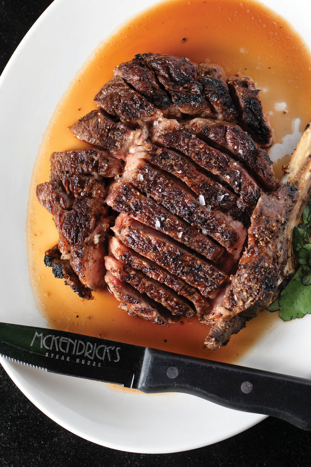 24-ounce rib eye sits on a plate in a pool of juice