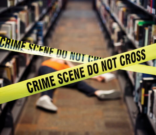 At this Decatur library, true crime lovers come together for Murder & Mocktails a person laid on the floor between two book isles is blocked off by yellow crime scene tape